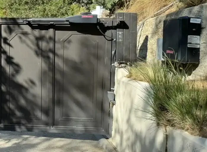 Automatic swing gate operator mounted on a dark driveway gate