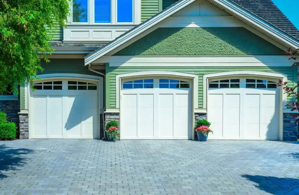 Three white carriage-style garage doors on a craftsman home