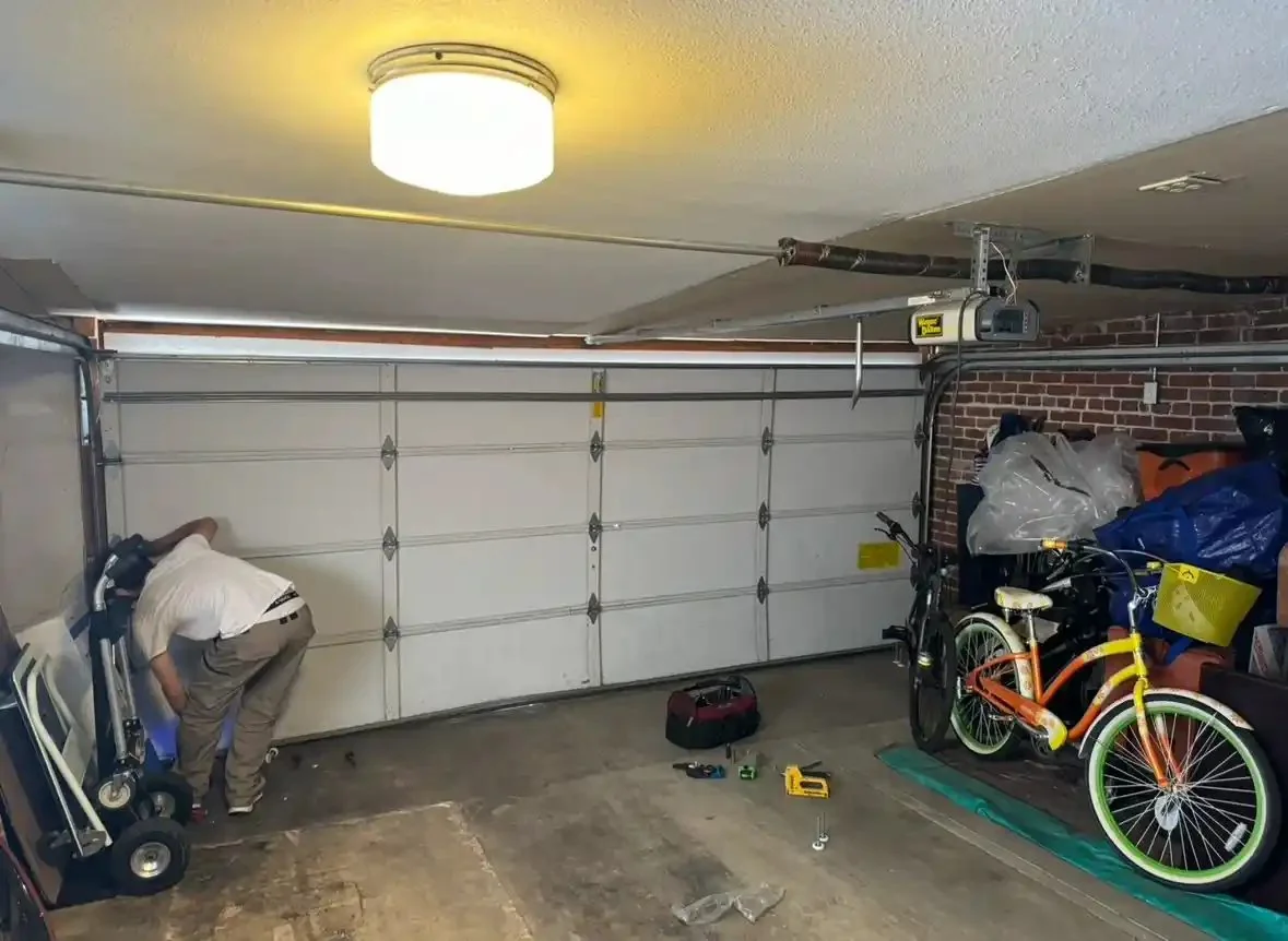 Technician working inside a garage with the door and opener track in view